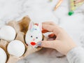 Hands of a caucasian girl in a gray turtleneck, laying an easter bunny egg with stickers in a cardboard box