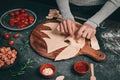 Hands of a Caucasian girl separate the Christmas tree from a thin one on pizza dough on a cutting board Royalty Free Stock Photo
