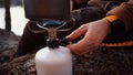 Hands caucasian male traveler, tourist sits in the forest near the lake camping. Uses inventory for cooking. A hand lighter set