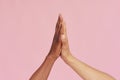 Hands of Caucasian man and black African American giving each other five on pink background. The concept of racism and