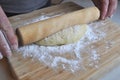 Hands of a Caucasian man rolling a pastry on a wooden board