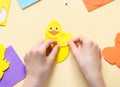 Hands of a caucasian teenage girl sticking a wing sticker on a yellow chicken felt with her fingers Royalty Free Stock Photo