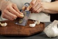 Hands of a caucasian woman grating garlic cloves using shovel shaped metal mini grater