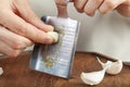 Hands of a caucasian woman grating garlic cloves using shovel shaped metal mini grater