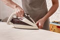 Hands of a caucasian woman holding an iron. Woman is ironing clothes on an ironing-board. Housework. Close-up Royalty Free Stock Photo