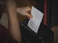 Hands of a ccaucasian young man is destroying documents in a black shredder Royalty Free Stock Photo