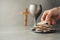 Hands with chalice and communion matzo bread, wooden cross on grey background. Christian communion for reminder of Jesus sacrifice Royalty Free Stock Photo