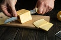 Hands of a chef with a knife slicing cheese on a cutting board in a restaurant kitchen. Preparing dairy food for breakfast while Royalty Free Stock Photo