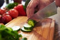 Hands of chef slicing cucumber with a knife on chopping board Royalty Free Stock Photo