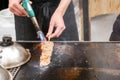 Hands of chef using burner cooking and burn Kobe beef stick on a hot pan to sale for customer at Kuromon market. Kobe beef stick