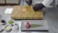 Hands of chef in white restaurant uniform cutting small salmon fish