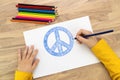 Hands of child drawing Peace symbol with blue pencil. World peace concept Royalty Free Stock Photo