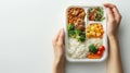 Hands of a child holding a plastic tray with unappetizing school lunch. Unappealing basic meal. Generative AI Royalty Free Stock Photo