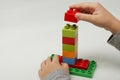 Hands of the child lay a pyramid of colorful cubes on white background