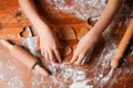 Hands of child makes biscuits cookies as hearts out of dough. Heart molds, rolling pin and flour on a table. Valentines