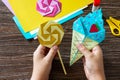 In the hands of a child origami paper ice cream and lollipop on a wooden table.