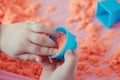 The hands of a child playing with kinetic sand