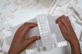 Hands of child playing with white Lego bricks in the Turbine Hall at Tate Modern, London UK.