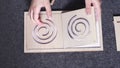 Hands of child taking out template in form of round maze and sheet of white paper with contours of this maze drawn on it