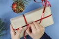 Hands of a child unpacking a new year`s gift, top view, blue background-the concept of receiving pleasant new year`s gifts