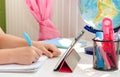 Hands of a child writing homework with tablet and stationery on white desk. Education Royalty Free Stock Photo