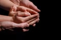 Hands of children and parents holding and supporting each other on a black background Royalty Free Stock Photo