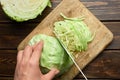 Hands chopping fresh green cabbage on wooden board with half a head of cabbage. Royalty Free Stock Photo