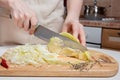 Hands chopping fresh green cabbage on wooden board with half a head of cabbage. Healthy vegan salad Royalty Free Stock Photo