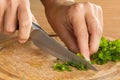 Hands chopping parsley leaves on the cutting board, closeup