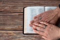 Hands of Christian couple wearing rings holding an open Holy Bible Book placed on wooden background with copy space Royalty Free Stock Photo