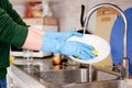 Hands cleaning dirty dishes in the kitchen