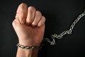 Hands clenched into fists in handcuffs in the form of chains on a black background, the problem of slavery and violence concept, Royalty Free Stock Photo