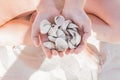 Hands of a close-up girl hold a bunch of seashells on the beach white sand background Royalty Free Stock Photo