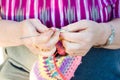 View of hands close-up of an old lady knitting on knitting needles, using colorful wool