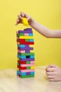 Hands close up playing a round of family game removing blocks from the tower made from colorful wooden blocks. Planning, risk, and