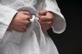 Hands closeup - teenager dressed in martial arts clothing posing on a dark gray background, a sports concept