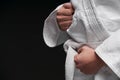 Hands closeup - teenager dressed in martial arts clothing posing on a dark gray background, a sports concept