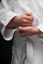 Hands closeup - teenager dressed in martial arts clothing posing on a dark gray background, a sports concept