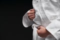 Hands closeup - teenager dressed in martial arts clothing posing on a dark gray background, a sports concept