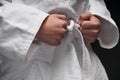 Hands closeup - teenager dressed in martial arts clothing posing on a dark gray background, a sports concept