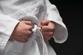 Hands closeup - teenager dressed in martial arts clothing posing on a dark gray background, a sports concept