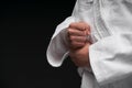 Hands closeup - teenager dressed in martial arts clothing posing on a dark gray background, a sports concept