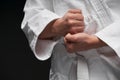 Hands closeup - teenager dressed in martial arts clothing posing on a dark gray background, a sports concept