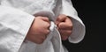 Hands closeup - teenager dressed in martial arts clothing posing on a dark gray background, a sports concept