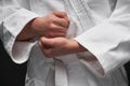 Hands closeup - teenager dressed in martial arts clothing posing on a dark gray background, a sports concept