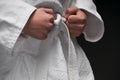 Hands closeup - teenager dressed in martial arts clothing posing on a dark gray background, a sports concept