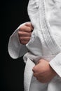 Hands closeup - teenager dressed in martial arts clothing posing on a dark gray background, a sports concept