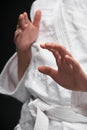 Hands closeup - teenager dressed in martial arts clothing posing on a dark gray background, a sports concept
