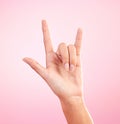 Hands, closeup and woman in studio with rock and roll sign, gesture or symbol against pink background. Zoom, rebel and Royalty Free Stock Photo