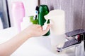 Hands collect liquid soap in a proximity sensor, near the sink with a tap in the bathroom